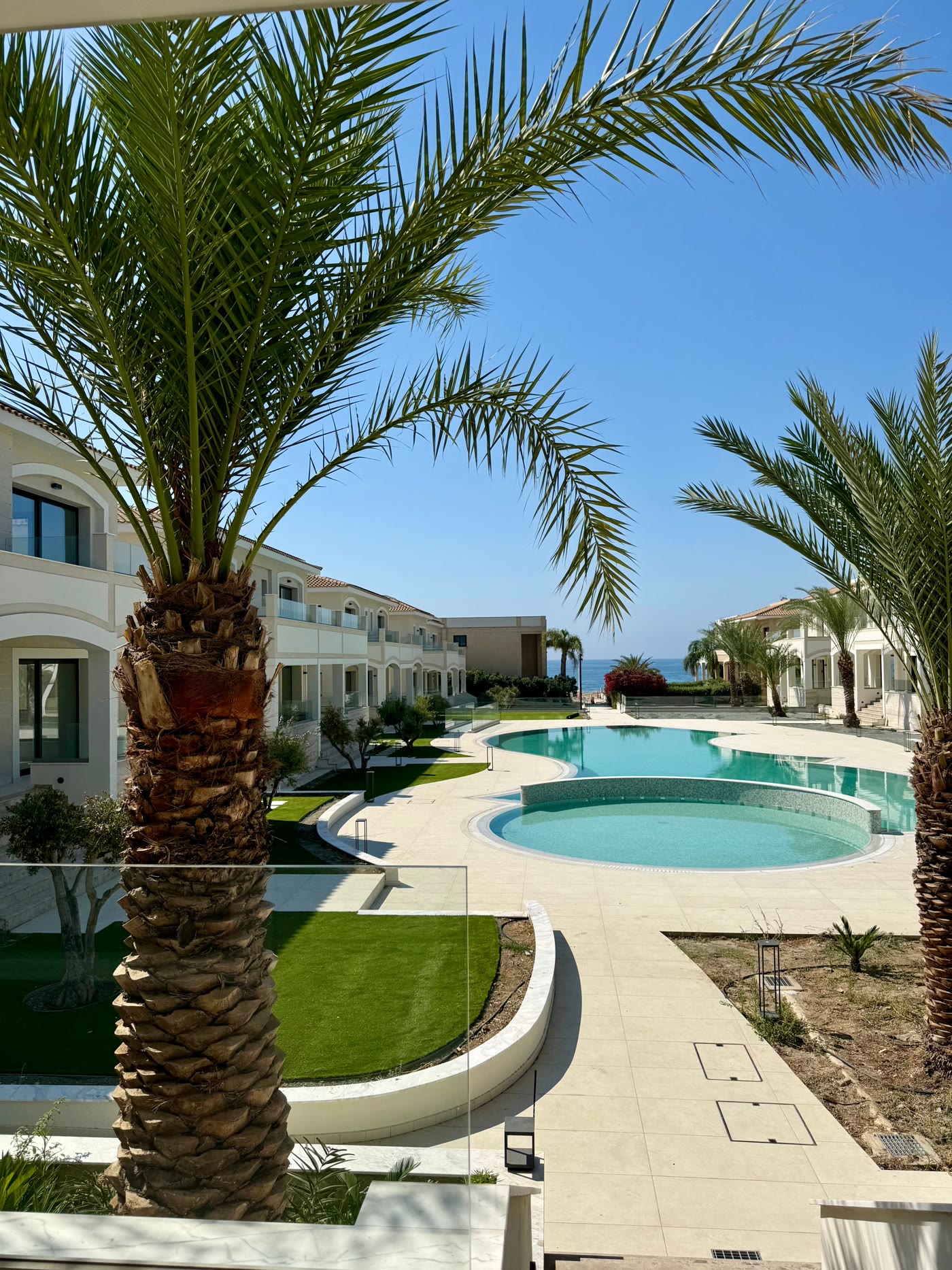 Palms framing the lagoon pool, with the sea at the end of the garden